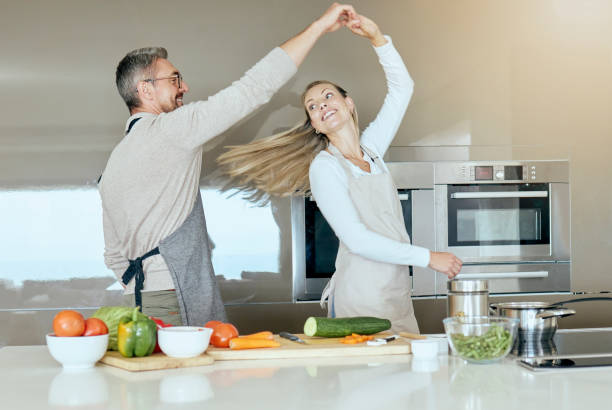istock Dancing couple, cooking and love in the kitchen while preparing vegetables for a healthy, organic and vegan meal or salad. Happy man and woman with energy, joy and good health having fun at home 1441579144