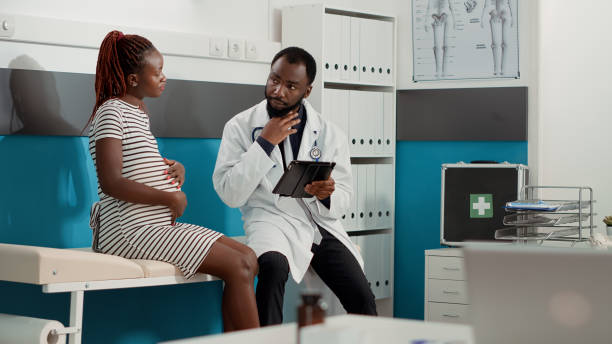istock Male obstetrician taking notes on digital tablet at checkup visit 1441579553