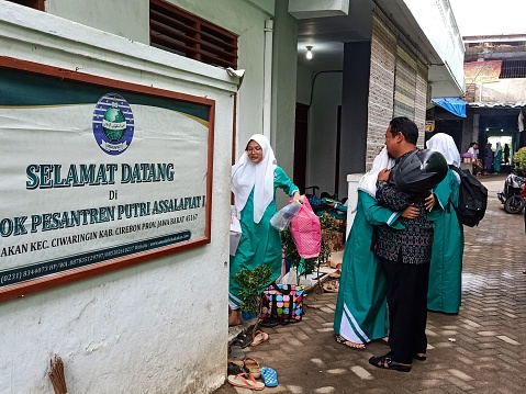 west, Indonesia – October 09, 2022: A moslem girl hugs her father who takes her to go back to boarding school