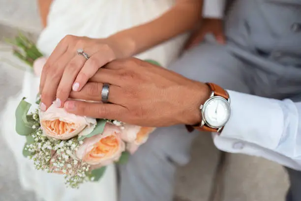 A closeup shot of a just-married groom and brides hands in rings