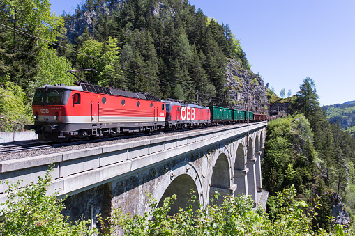 Semmering, Austria – May 30, 2021: Austrian OEBB cargo train passing a viaduct at the Semmering mountain rail