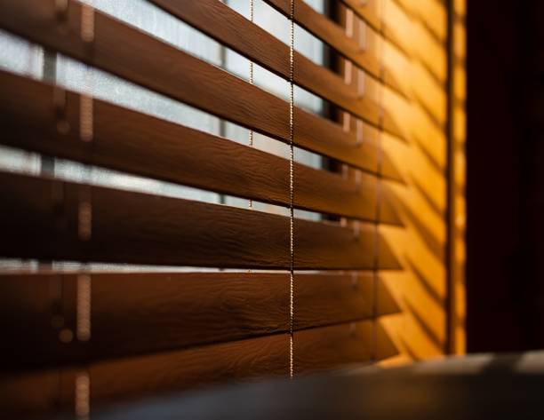 istock Wooden blinds next to a window with sunlight on the side 1441583862