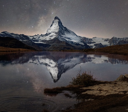 Matterhorn with milky way galaxy reflected in lake stellisee at night in switzerland.