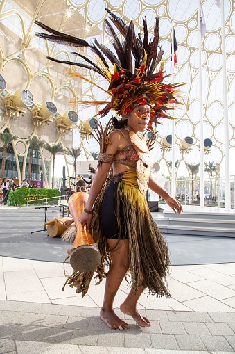 du, United Arab Emirates – February 28, 2022: Papua New Guinea Island first nation dancers at Expo2020 dancing in traditional clothes with feathers and bright colours face painted ocra