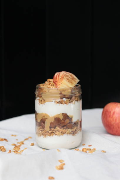 istock Delicious apple parfait in a jar on a white table cloth, isolated on a black background 1441587026