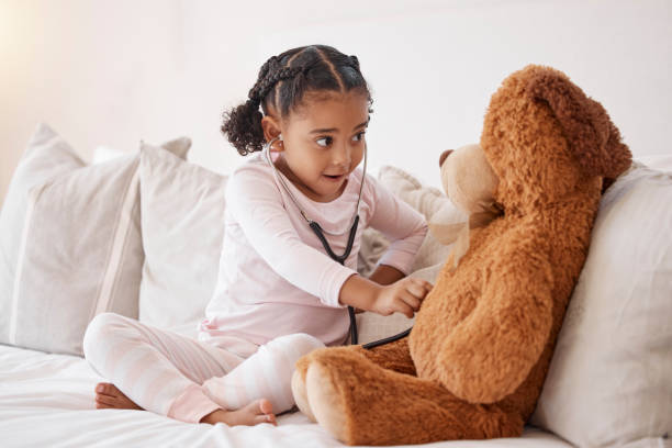 niño con estetoscopio revisa el osito de peluche con amor, atención médica o desarrollo infantil en su habitación. niña inteligente o bebé con muñeca en juego juego de simulación para diversión, mente sana y educación - niño pre escolar fotografías e imágenes de stock