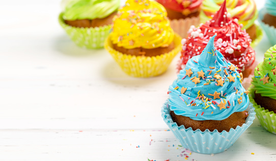 Colorful cupcakes on wooden table. With copy space