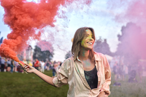 One woman dancing with coloured smoke bombs at Holi Festival