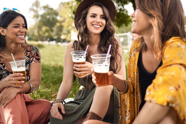 istock Three women sitting at the grass and drink beers 1441599768