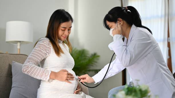 medico asiatico o ostetrico che ascolta il battito cardiaco del bambino dal suo stetoscopio. - abdomen gynecological examination women loving foto e immagini stock