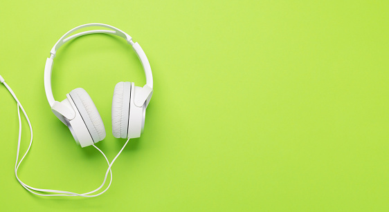 Headphones on green background. Flat lay with copy space