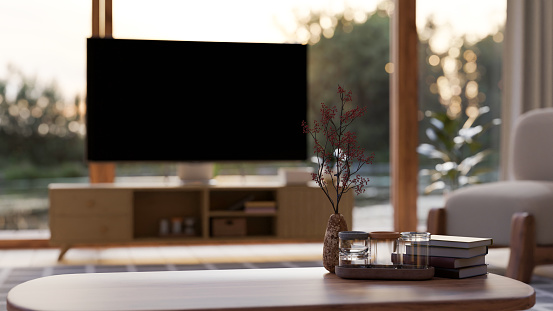Copy space for your product display on wood coffee table with decor over blurred living room with television in the background. close-up image. 3d render, 3d illustration