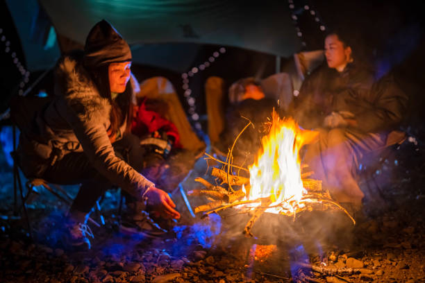 The campers are happily warming themselves by fire