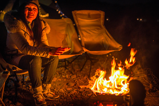 The campers are happily warming themselves by fire