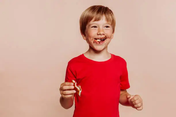 Photo of Little cute cheerful kid eats chocolate bun