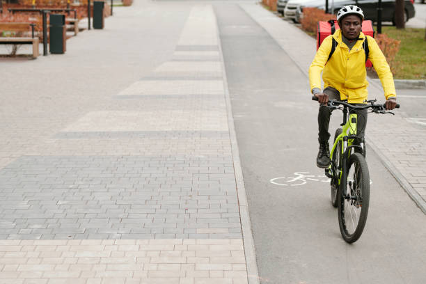 istock Young African American male courier with backpack riding bicycle 1441604809