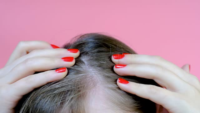 Girl touching her hair close-up on pink background , hair loss concept.