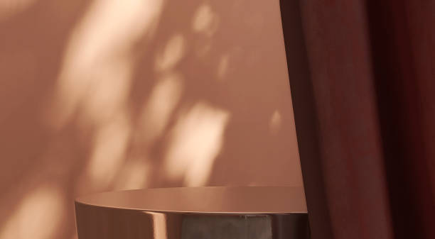 istock Gold colored steel side table podium and maroon red curtain with dappled sunlight from window on brown wall 1441607552