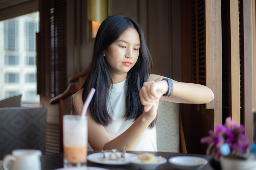 Woman having breakfast and looking at wrist watch