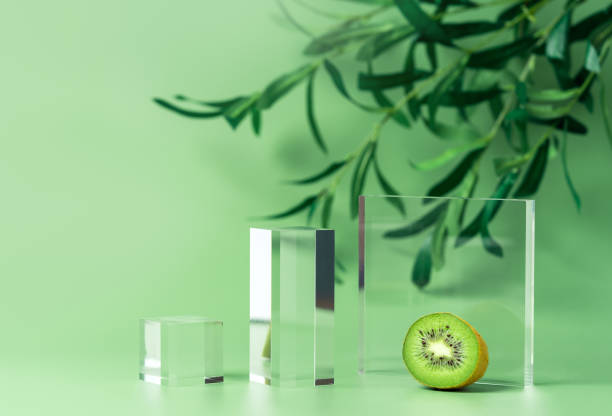 Front view mockup empty glass stage for cosmetic product presentation on natural background with olive tree branch and kiwi slice.