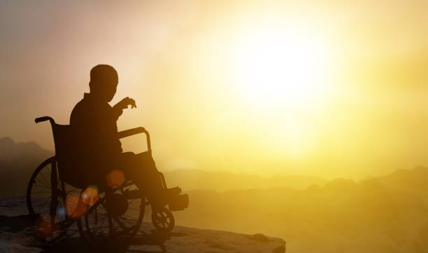 un homme handicapé a un espoir sur le fauteuil roulant ont un fond de coucher de soleil. challenger and conquer succès et concept de santé. la silhouette de la personne est assise en tendant les mains au coucher du soleil. - wheel incentive winning award photos et images de collection