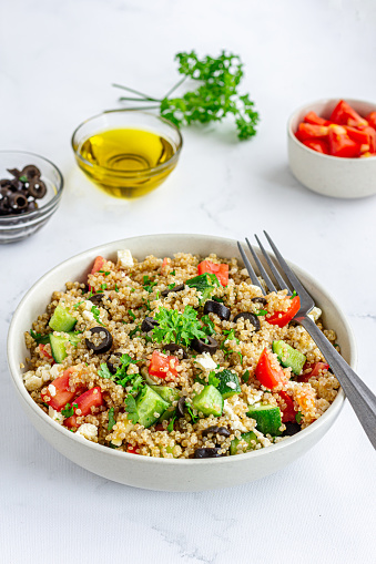 Healthy Quinoa Salad in a Bowl with Olive Oil, Olive, Parsley on White Background