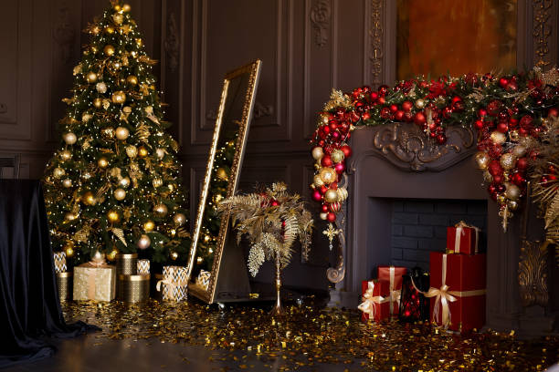 벽난로, 편안한 소파, 크리스마스 트리와 선물로 장식된 샹들리에가 있는 고급스럽고 어두운 거실의 인테리어 - christmas tree christmas fireplace christmas lights 뉴스 사진 이미지