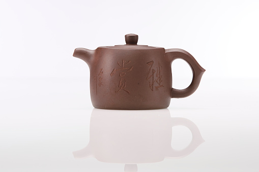 White ceramic kettle with a few mint leafs aside, on a wooden table