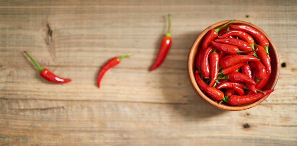 Red hot chili pepper with bowl on old wooden background.