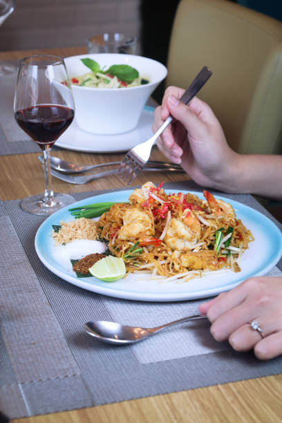 istock A Plate of “Phad Thai” with prawn on table with hands holding spoon and fork 1441619066