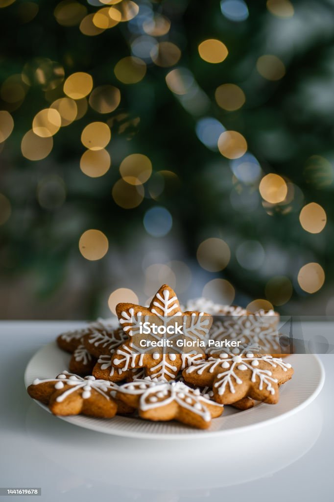 Ginger Christmas cookies on the background of a Christmas tree with lights. Ginger Christmas cookies on the background of a Christmas tree with lights. Front view. Christmas Stock Photo