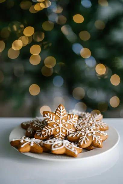 Ginger Christmas cookies on the background of a Christmas tree with lights. Front view.