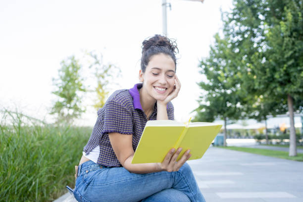 istock Happy woman sitting outdoors and reading a book 1441620750