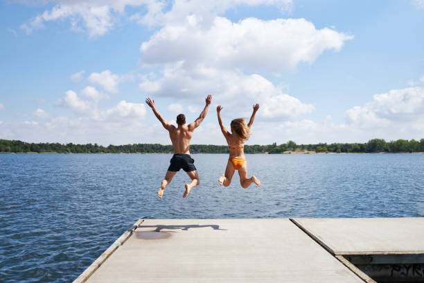 istock A young couple jumps off a pier into a lake 1441622083