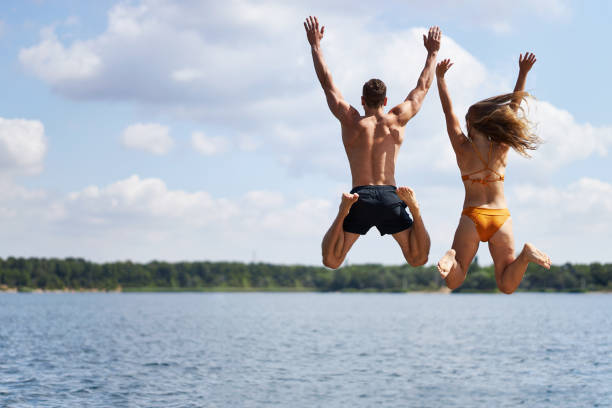 istock A young couple jumps off a pier into a lake 1441622136