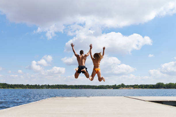 istock A young couple jumps off a pier into a lake 1441622178