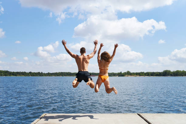 istock A young couple jumps off a pier into a lake 1441622217