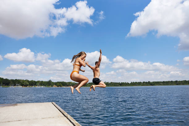istock A young couple jumps off a pier into a lake 1441622939