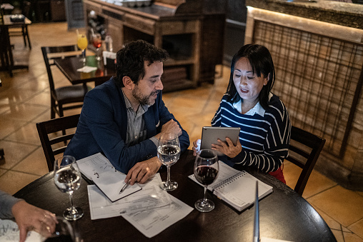 Coworkers doing a meeting using digital tablet at a bar