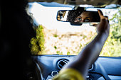 Selective focus shot of young woman adjusting a rear view mirror in her new car