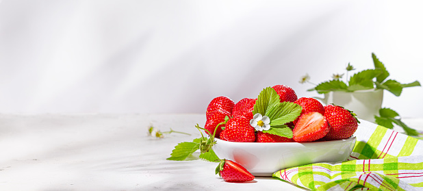 Fresh strawberries in a bowl on white stone table, banner. Still life with selective focus and copy space for text