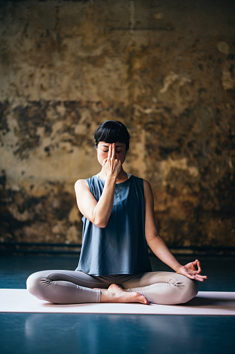 Beautiful Asian woman in sportswear doing breathing exercise in the yoga studio.