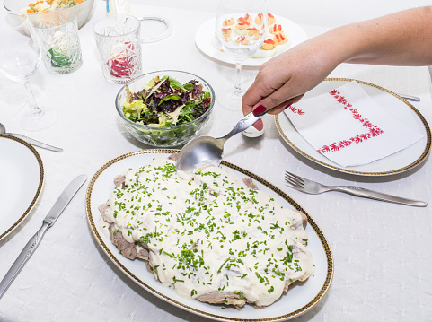 Mature woman serving vitello tonnato, dish of very traditional Italian origin in Argentina for Christmas and summer,