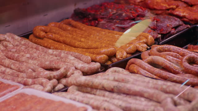 Close up raw meat sausages on the supermarket shelves assortment on showcase in a butcher shop.