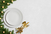 Christmas golden table setting and on a gray background. Empty plate for design. New Year party. Copy space, top view, flat lay.