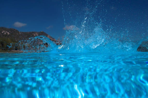 Blue water with ripples on the surface. Defocus blurred transparent blue colored clear calm water surface texture with splashes and bubbles. Water waves with shining pattern texture background.