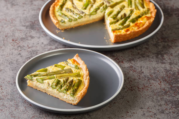 French cream tart with fresh asparagus, eggs and cheese close-up in a plate on the table. Horizontal