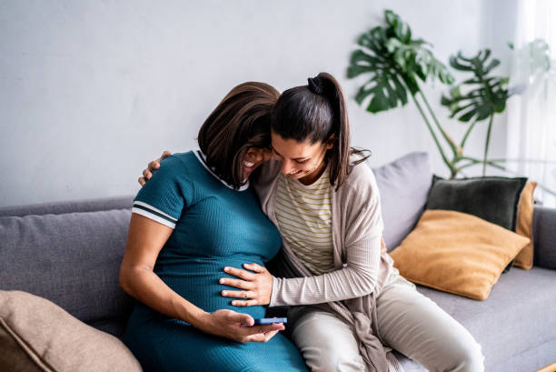 istock Pregnant lesbian couple using mobile phone at home 1441645284