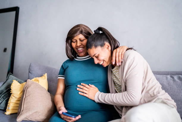 istock Pregnant lesbian couple using mobile phone at home 1441645288