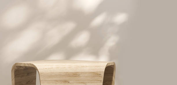 istock Modern and minimal geometric shape wooden pedestal table with dappled sunlight and leaf shadow on beige wall 1441645775